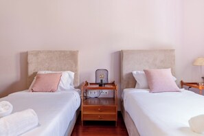A hotel room with two beds, each with a headboard, a bedside table with a lamp, and a power outlet. - Casa das Andorinhas by Hommelier (Fão)