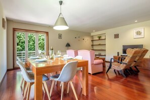 Un coin repas avec une table en bois dressée pour quatre personnes, une chaise rose et un fauteuil à motifs.