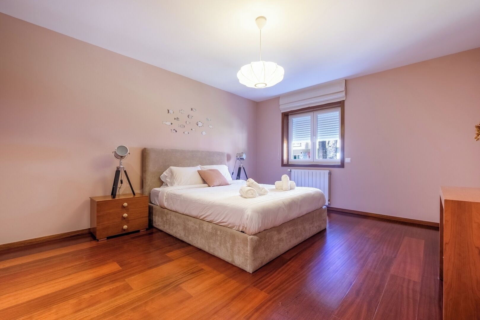 Une chambre à coucher avec un lit, des tables de chevet, une fenêtre et un luminaire au plafond.