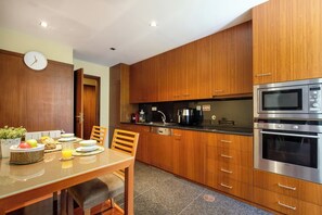 Une cuisine moderne avec des meubles en bois, des appareils en acier inoxydable et un coin repas avec une table mise pour deux personnes.