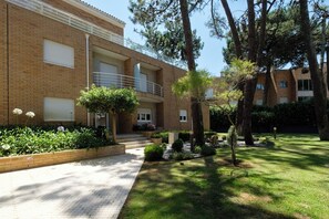 A multi-story residential building with a brick facade, a covered outdoor area with a staircase, and a well-maintained garden with various plants and trees. - Casa das Andorinhas by Hommelier (Fão)