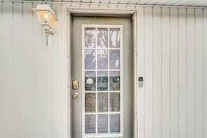 Eine weiße Tür mit Fenster, Klingel und einer Wandleuchte.