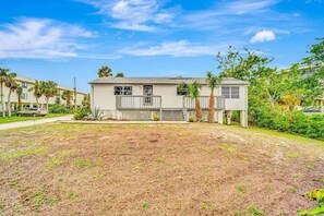 A single-story building with a front porch, a small attached garage, and a fenced yard. - Newly Renovated Beach Retreat Just Steps from Englewood Beach - Beach Barracks - Roelens (Englewood)