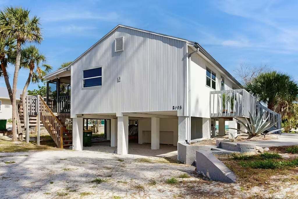 A modern two-story house with a covered patio and a staircase leading to a deck.