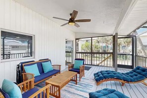 Ein überdachter Außenbereich mit Deckenventilator, Holzmöbeln und Blick ins Freie.