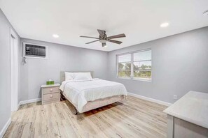 Una camera da letto con un letto, un comodino, una ventola a soffitto, una finestra e una panca integrata.