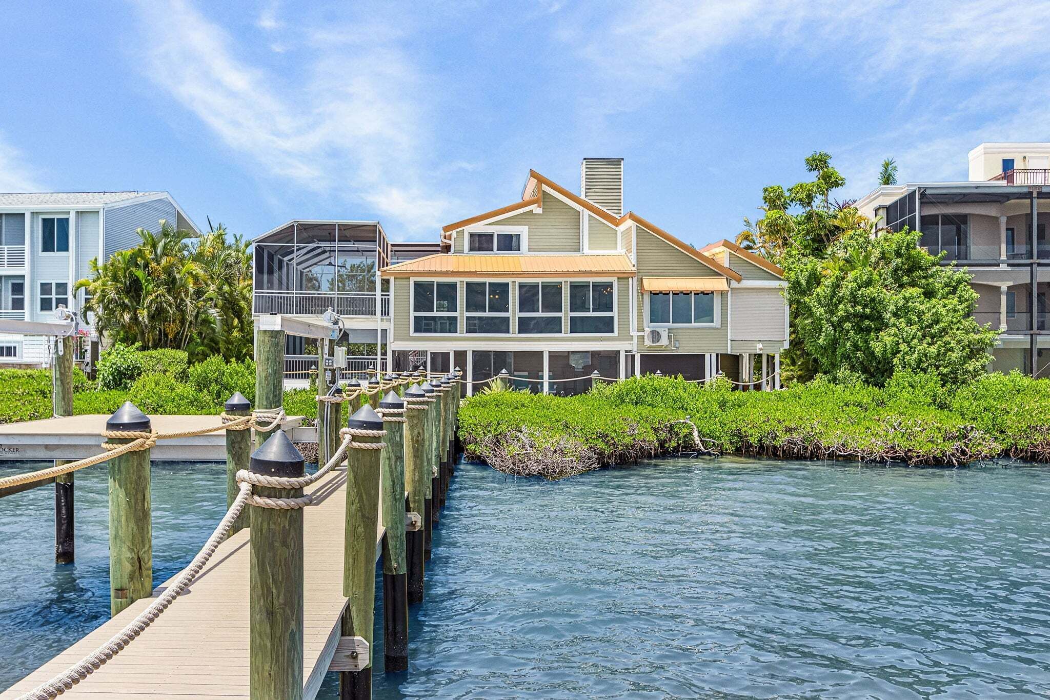 A waterfront property with a dock, a building with large windows, and a clear sky.