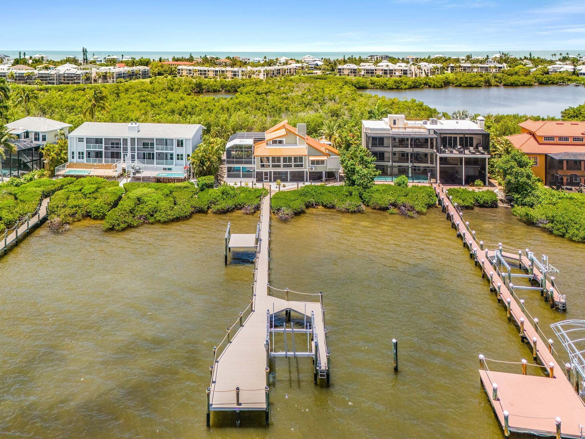 A waterfront property with multiple buildings, a dock, and a clear view of the ocean.