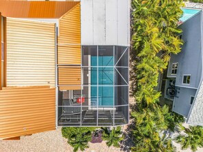 Eine Luftaufnahme eines Wohnhauses mit Swimmingpool, Holzterrasse und umgebender Bepflanzung.