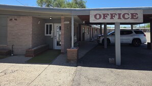 A building with an 'OFFICE' sign, a covered entrance, and a parked white SUV. - Desert Inn and RV (Shoshoni)