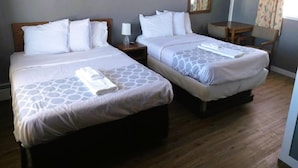 A hotel room with two beds, a small table, and a chair. - Desert Inn and RV (Shoshoni)