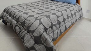 Een slaapkamer met een bed, een kroonluchter, een raam met zonwering en een airconditioning.