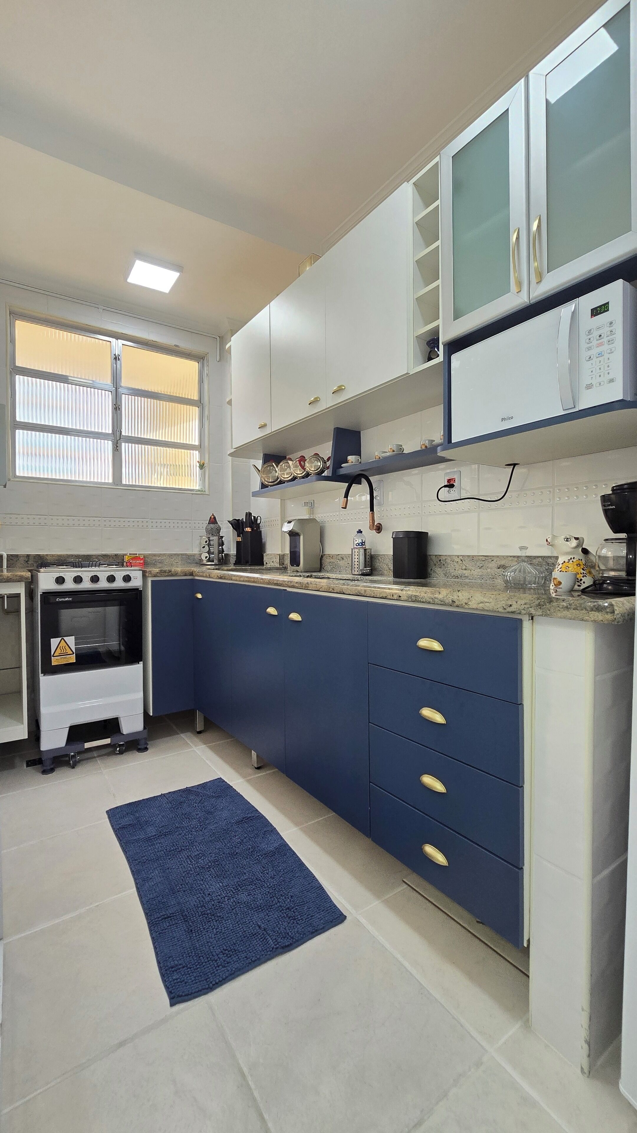 A modern kitchen with white cabinets, a built-in oven, a microwave, and a coffee maker.