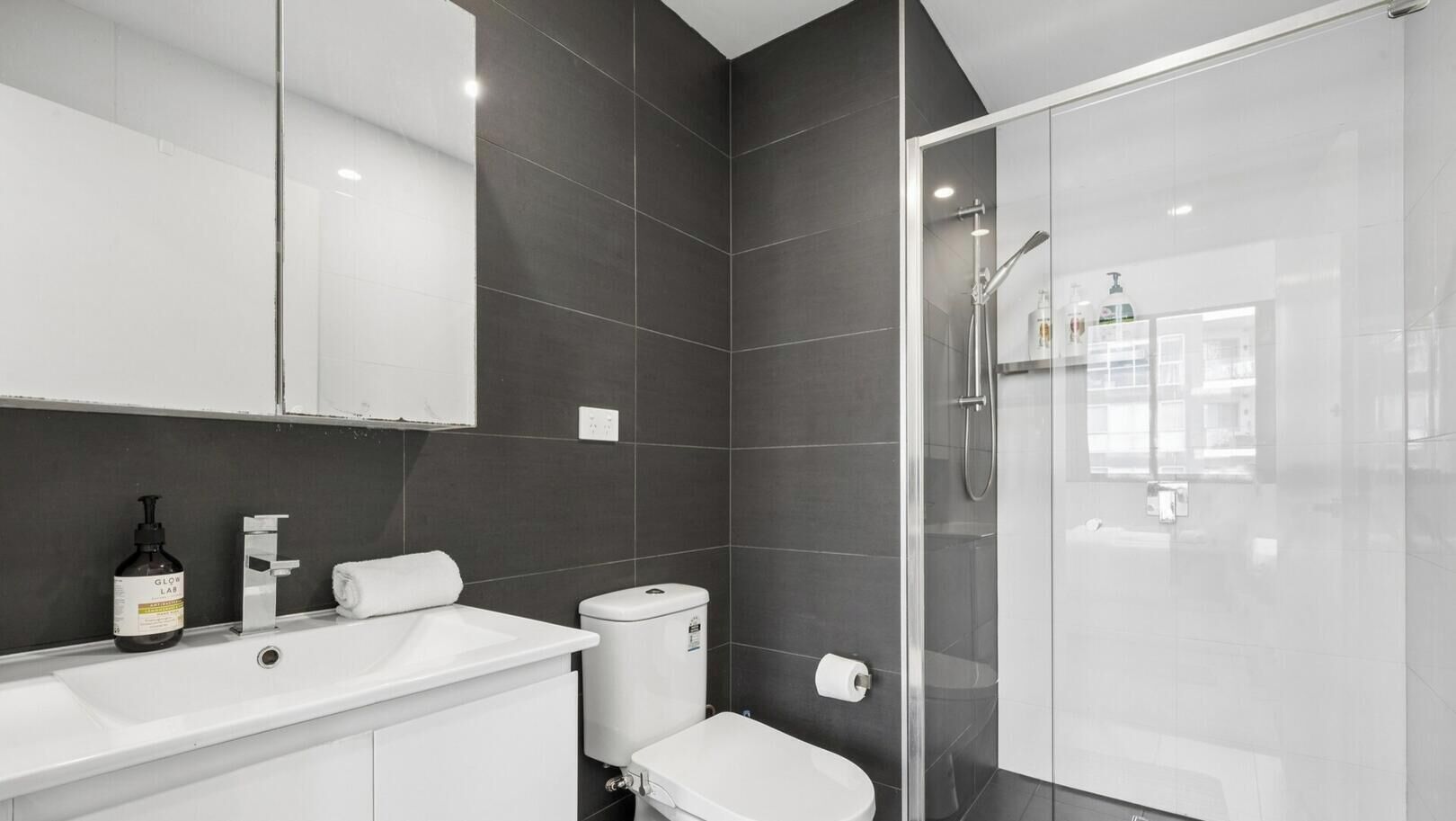 Une salle de bain moderne avec une douche à parois de verre, un lavabo blanc et des toilettes.