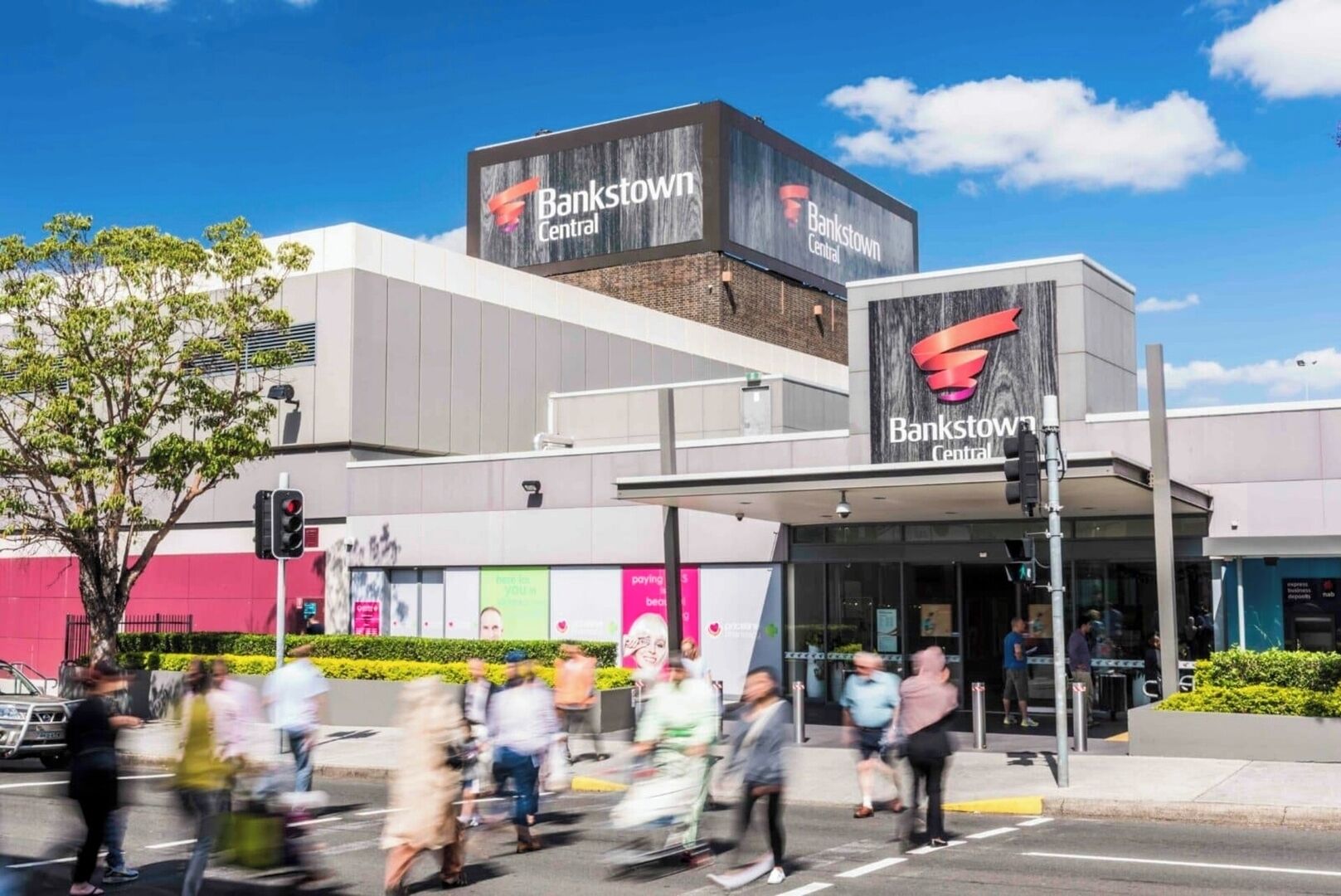 A modern building with a prominent Bankstown Central sign, a pedestrian crossing, and a traffic light.