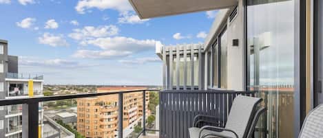A balcony with a view of surrounding buildings, a pergola, and outdoor seating.