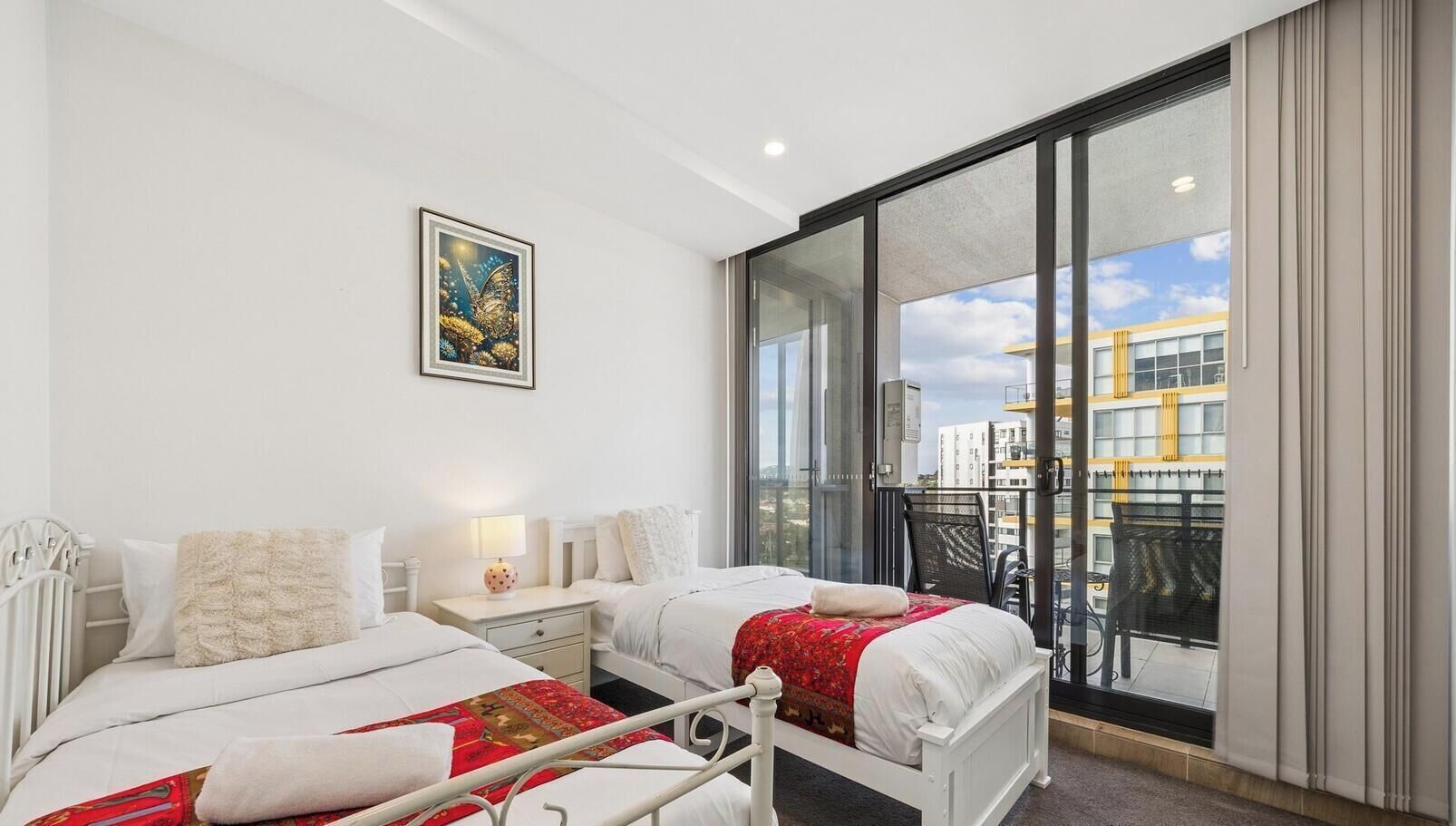 A hotel room with two beds, a large window, and a city view.