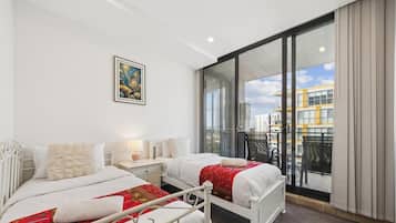 A hotel room with two beds, a large window, and a city view.