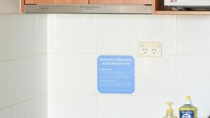 Een keuken met houten kastjes, een magnetron, een fornuis en een bordje waarop staat dat de keukenvoorzieningen uitsluitend bedoeld zijn voor het bereiden van eenvoudige maaltijden.