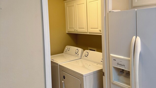 A laundry room with a washer and dryer, a refrigerator, and a cabinet. - Charming 2-bedroom condo on Lake Hamilton (Hot Springs)