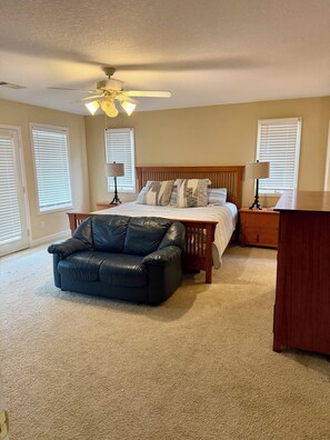A bedroom with a bed, two bedside tables, a ceiling fan, and a black leather ottoman. - Charming 2-bedroom condo on Lake Hamilton (Hot Springs)
