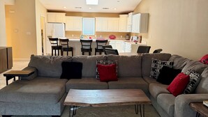 A living room with a sectional sofa, a coffee table, and a kitchen in the background. - Charming 2-bedroom condo on Lake Hamilton (Hot Springs)