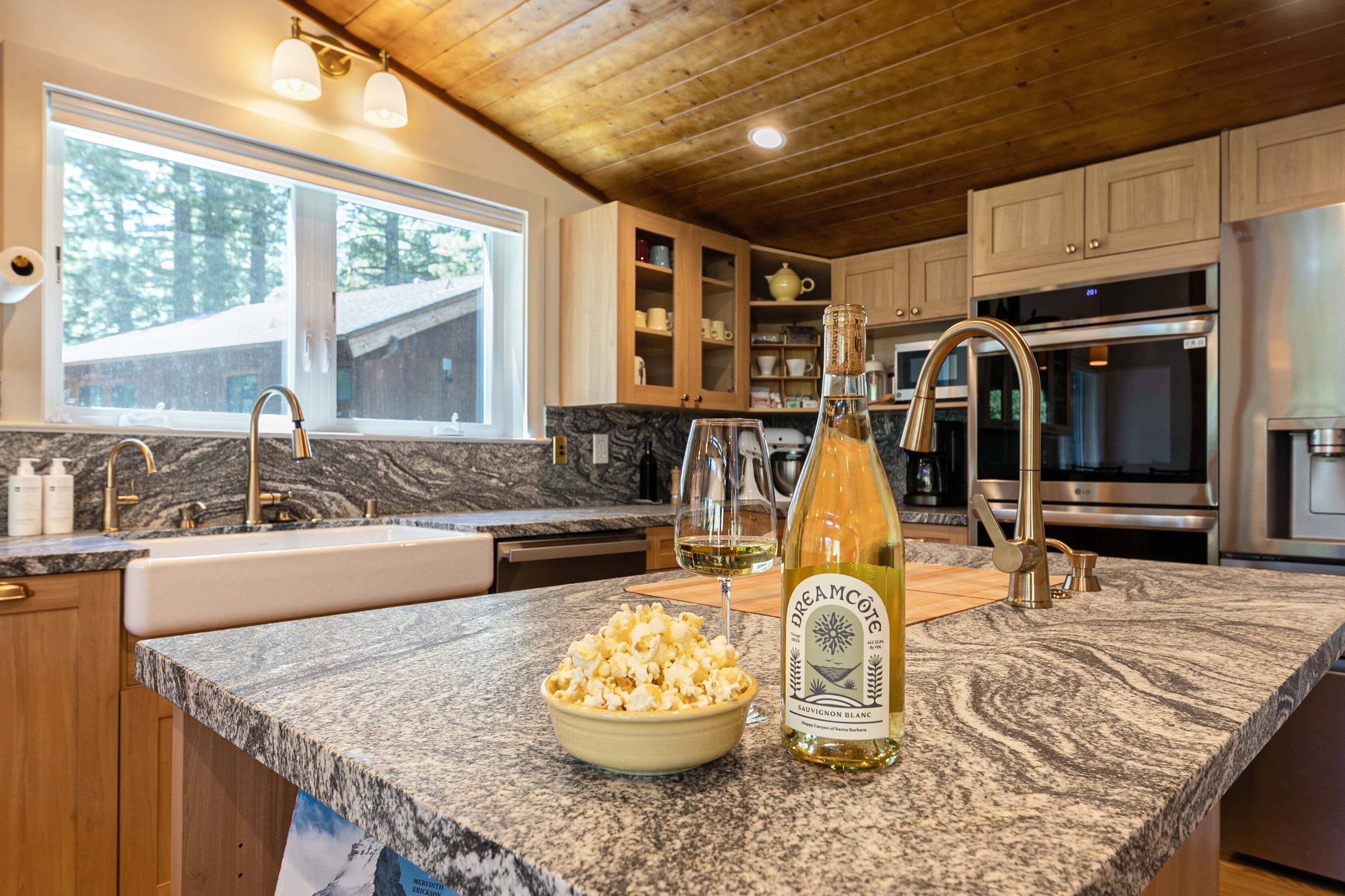 A kitchen with granite countertops, a wine bottle, and a bowl of popcorn.