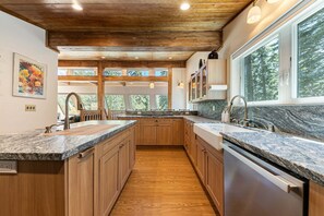 Eine Küche mit Holzausstattung, Granit Arbeitsplatten und einem Fenster mit Blick auf einen Wald.
