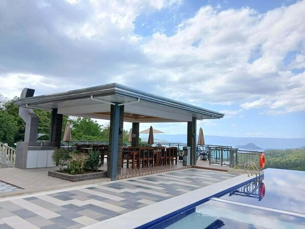 Zona de piscina exterior con área de descanso cubierta y vistas al paisaje.