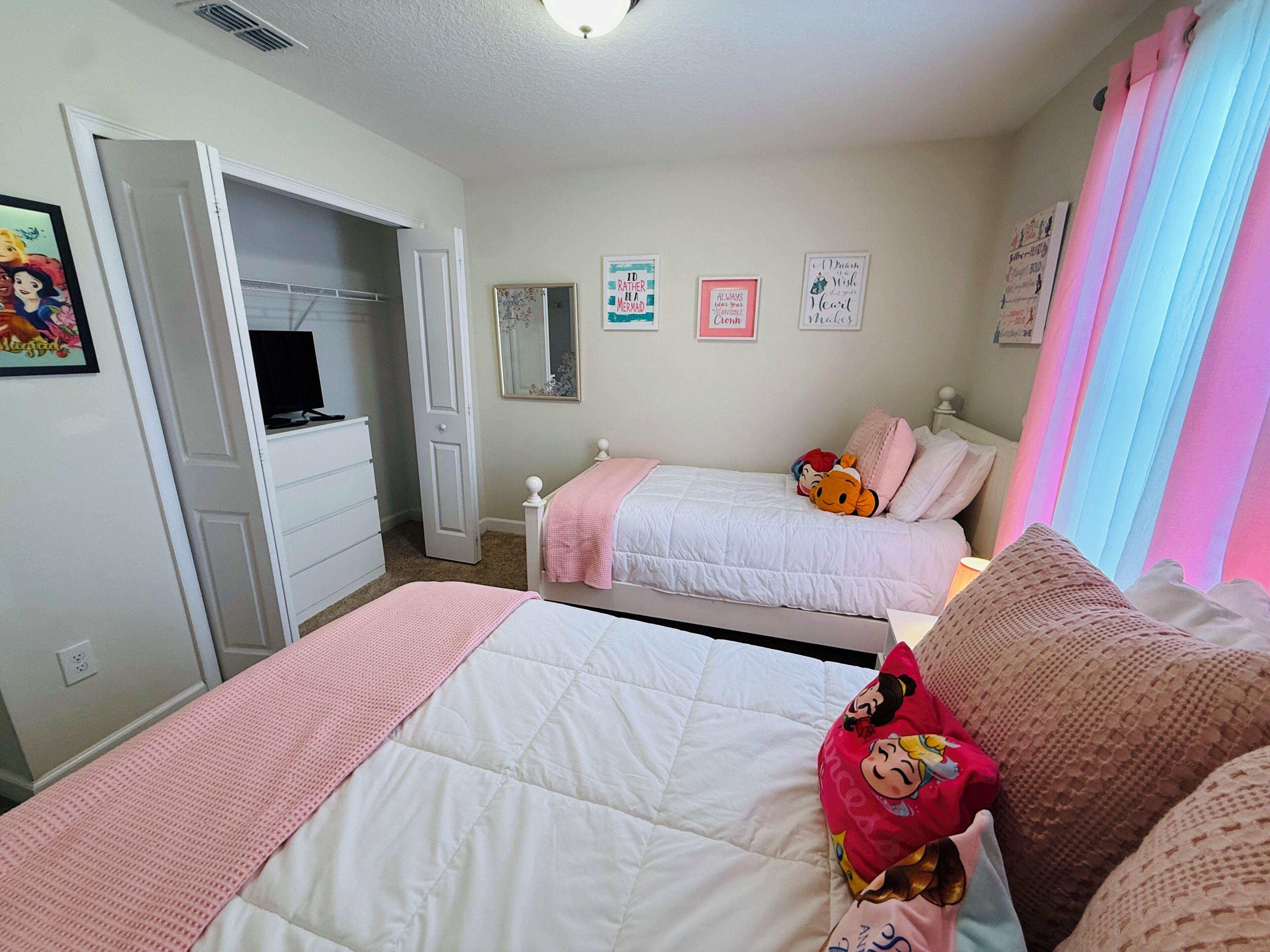 A bedroom with two beds, a wardrobe, a mirror, and motivational posters on the wall.