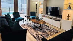 Uma sala de estar moderna com um sofá, uma mesa de centro, uma televisão e um abajur decorativo.