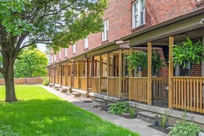 A row of brick townhouses with wooden balconies and a tree in the foreground. - Pet-Friendly 2BR in Merion Village (Columbus)