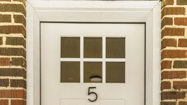 Puerta blanca con el número 5, un panel de vidrio y cerradura electrónica.