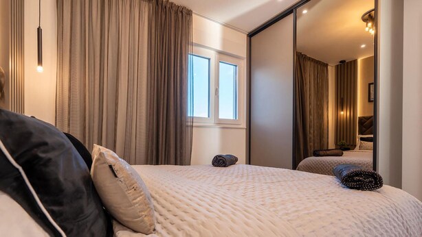 Une chambre à coucher avec un lit, des rideaux, une fenêtre et un miroir qui reflète la pièce.