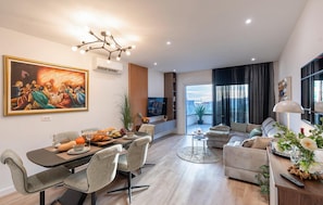 Ein modernes Wohnzimmer mit Essbereich, einer Sofagarnitur, einem Fernseher und einem großen Gemälde an der Wand.