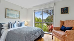 Une chambre à coucher avec un lit, une chaise, une fenêtre et un tableau.