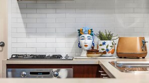 A kitchen with a Westinghouse stove, a decorative ceramic head, a potted plant, and a vintage toaster. - Saltwater Sanctuary | Fireplace & Walk to Beach (Mount Martha)
