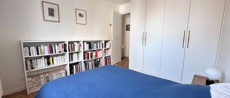 A bedroom with a large bed, a bookshelf, and a wardrobe.