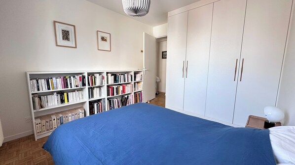 Um quarto com uma cama grande, uma estante de livros e um guarda-roupa.