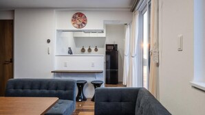 Una cocina moderna con un reloj, un refrigerador y un comedor con una mesa y sillas.