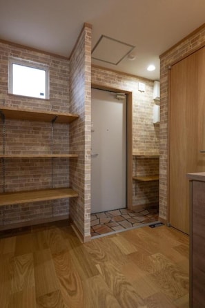 A room with brick walls, wooden flooring, and built-in shelves. - Ocean Stay (Shiraoi)