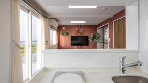 Una cocina moderna con un ventanal grande, horno empotrado y un televisor de pantalla plana en la pared.