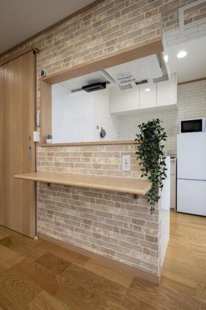 A kitchen with a brick wall, wooden shelves, and a hanging plant.