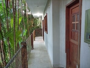 Un passadís amb una porta de fusta, una reixa de metall i un terra emplestrat.