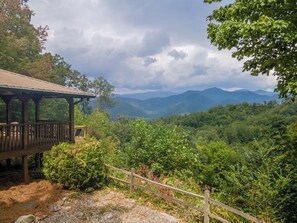 Eine Holzhütte mit überdachter Veranda, umgeben von dichtem Wald und Bergen im Hintergrund.