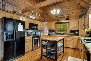 Eine gemütliche Holzblockküche mit Kühlschrank, Herd, Mikrowelle und Holzschränken.