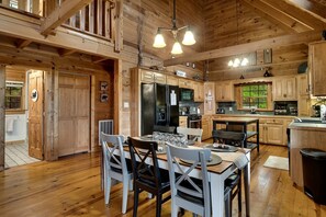 A spacious kitchen with wooden cabinets, a dining area with a table and chairs, and a large window. - Cherokee Lookout Point (Bryson City)