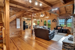 Ein Holzblockhaus-Interieur mit Wohnzimmer, Küche und Essbereich.