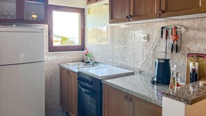 Een kleine keuken met een inbouwoven, een spoelbak en een raam.
