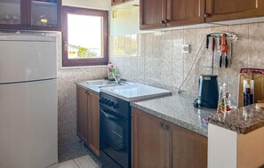 Eine kleine Küche mit Backofen, Spüle und Fenster.
